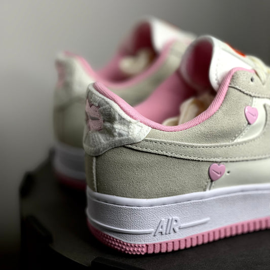 Gray sneakers with pink accents and heart designs on a neutral background