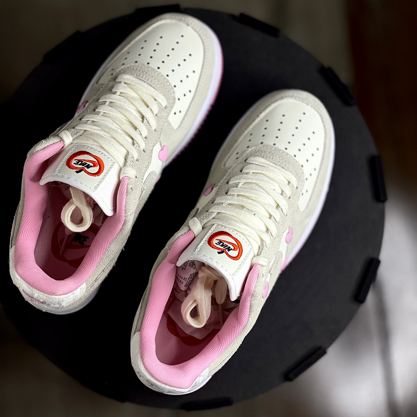 White sneakers with pink lining on a black circular platform