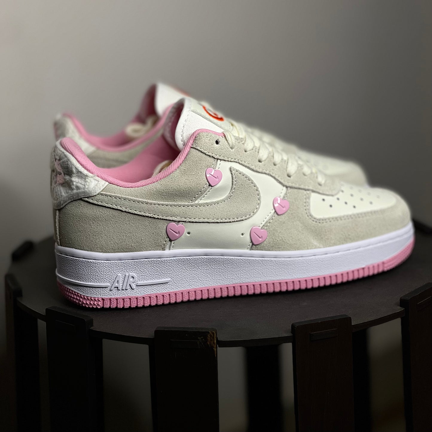 Gray and pink sneakers with heart patterns on a dark surface