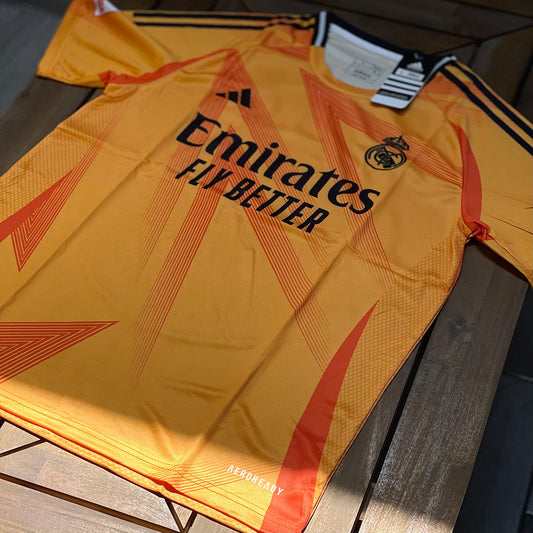 Yellow Real Madrid sports jersey with Emirates and Adidas logos on a wooden surface_2