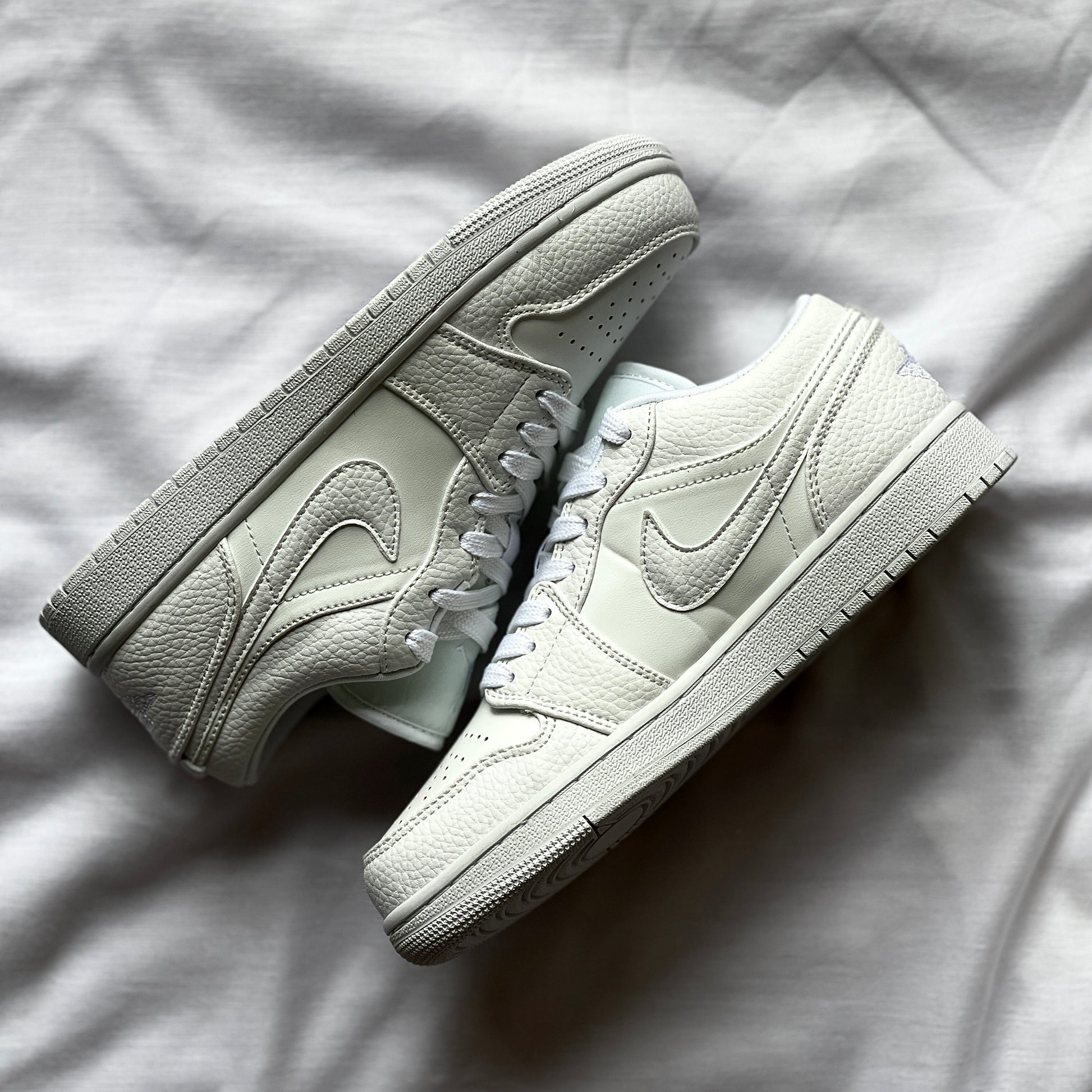 Side view of Air Jordan 1 Low Triple White showing all-white leather upper, white midsole, and classic low-top silhouette.