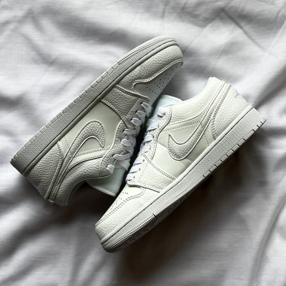 Side view of Air Jordan 1 Low Triple White showing all-white leather upper, white midsole, and classic low-top silhouette.