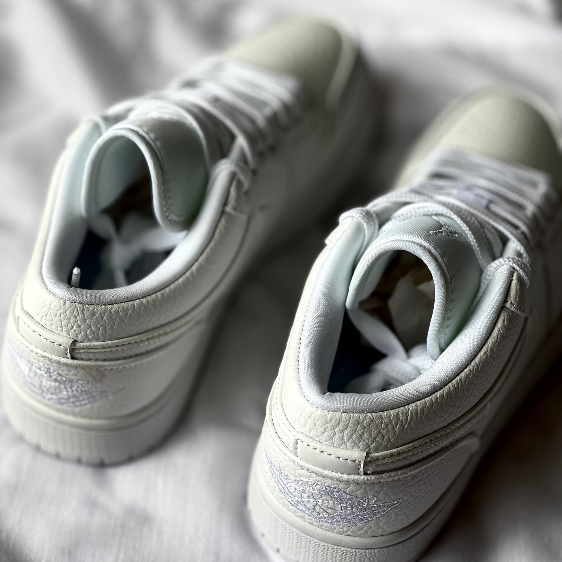 Rear view of Air Jordan 1 Low Triple White highlighting heel tab, stitching details, and clean silhouette.