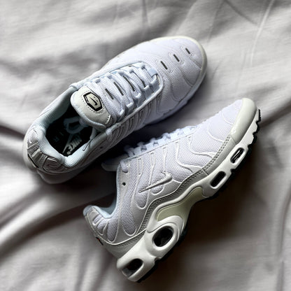 Close-up of Nike Air Max Plus Triple White showing wavy overlays, stitching, and Tuned Air details.