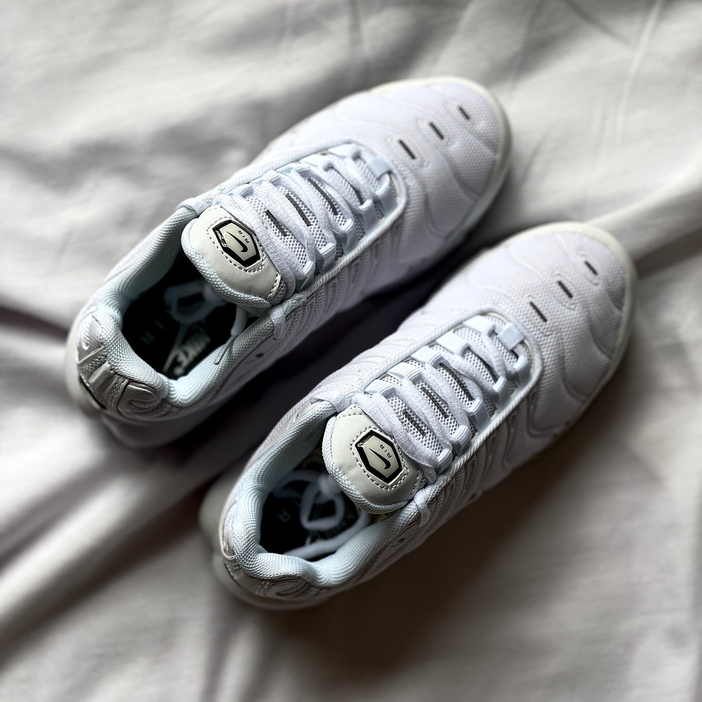 Top view of Nike Air Max Plus Triple White highlighting laces, tongue, and smooth synthetic upper.