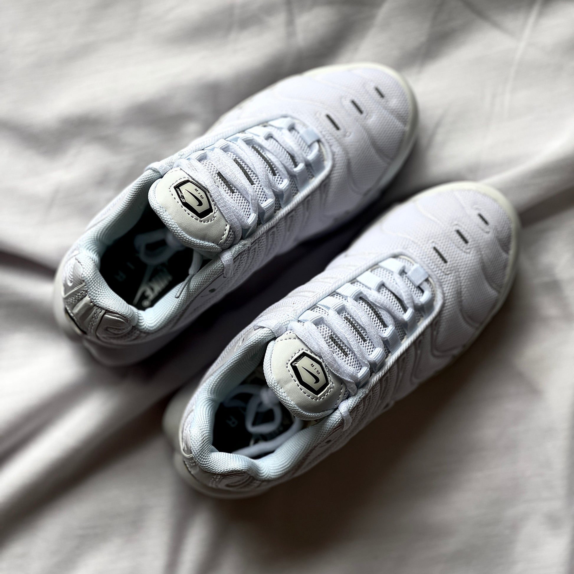 Top view of Nike Air Max Plus Triple White highlighting laces, tongue, and smooth synthetic upper.
