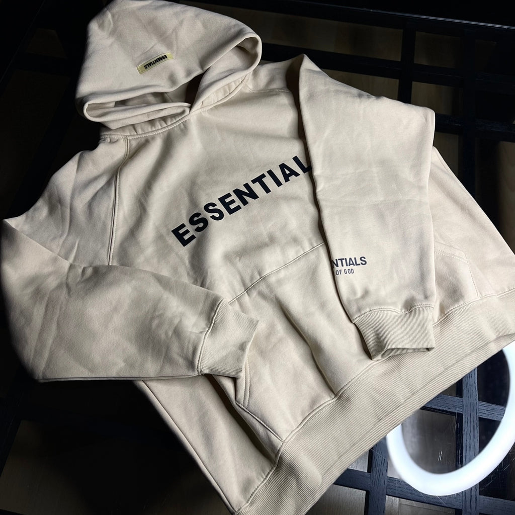 Fear of God Essentials Hoodie Dusty Beige front view — neutral beige oversized hoodie with minimalist logo branding