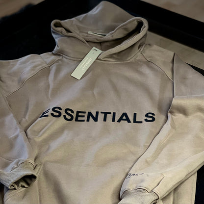 Close-up of Fear of God Essentials Hoodie Light Oatmeal fabric and logo patch — premium cotton-blend texture and subtle branding