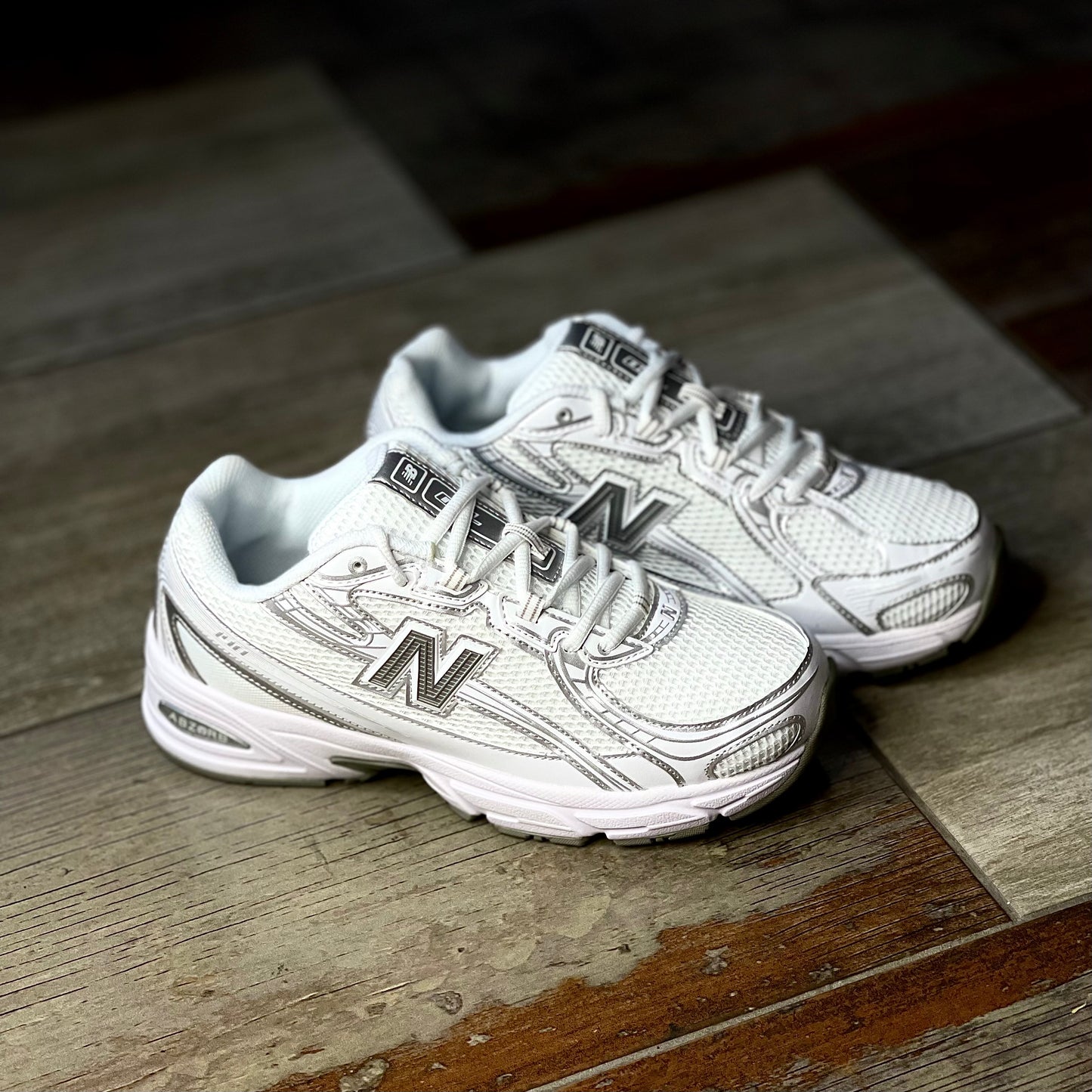 New Balance 740 V2 sneaker in white with silver reflective accents, side profile showing classic retro design.