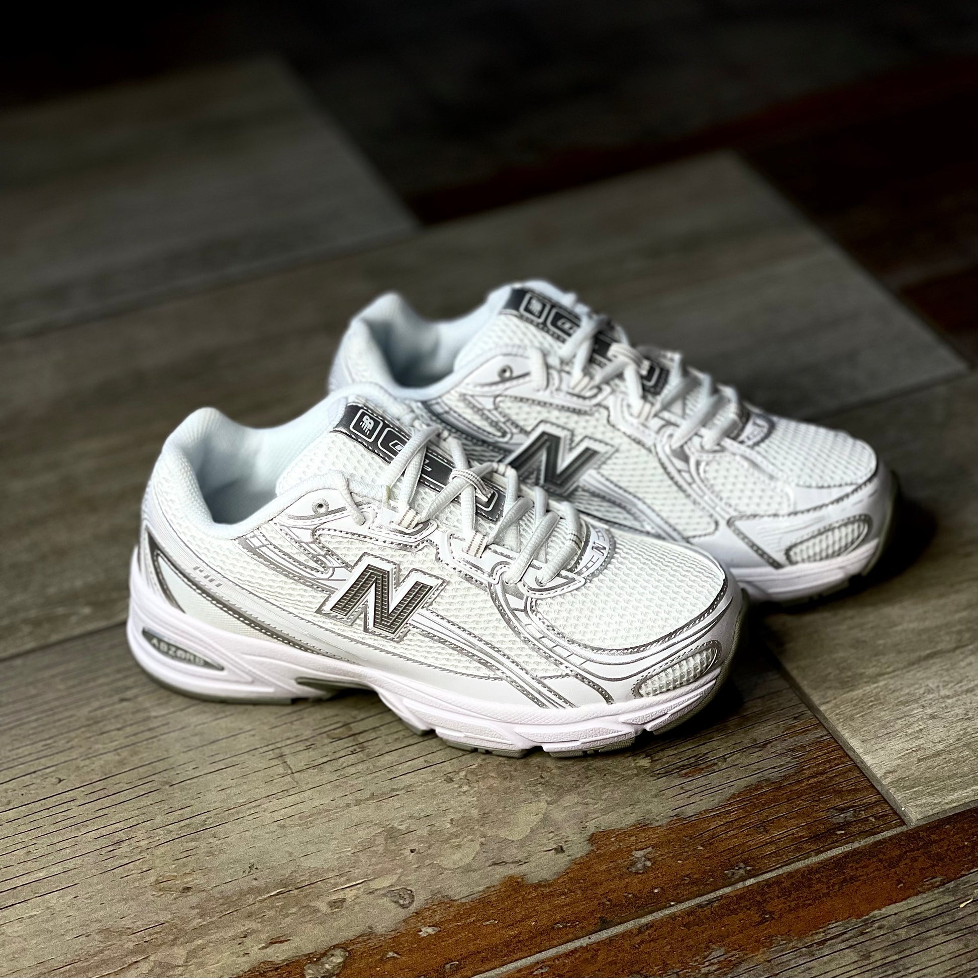 New Balance 740 V2 sneaker in white with silver reflective accents, side profile showing classic retro design.