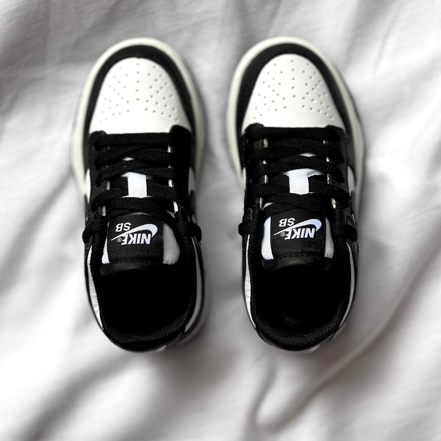Top view of Nike Dunk Low Panda kids’ sneaker highlighting laces, tongue, and two-tone leather upper.