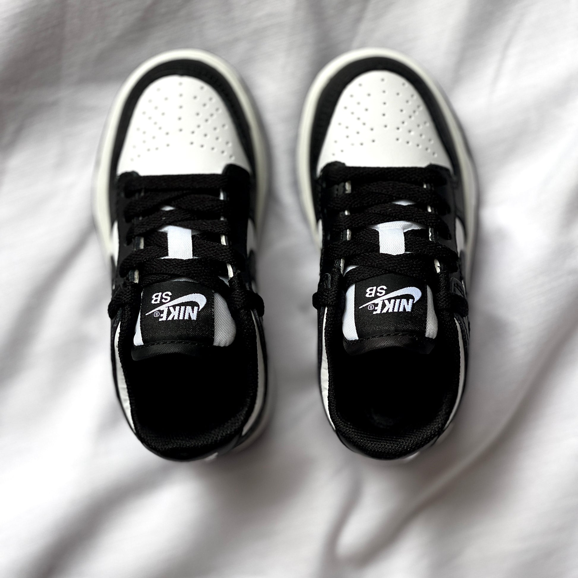 Top view of Nike Dunk Low Panda kids’ sneaker highlighting laces, tongue, and two-tone leather upper.