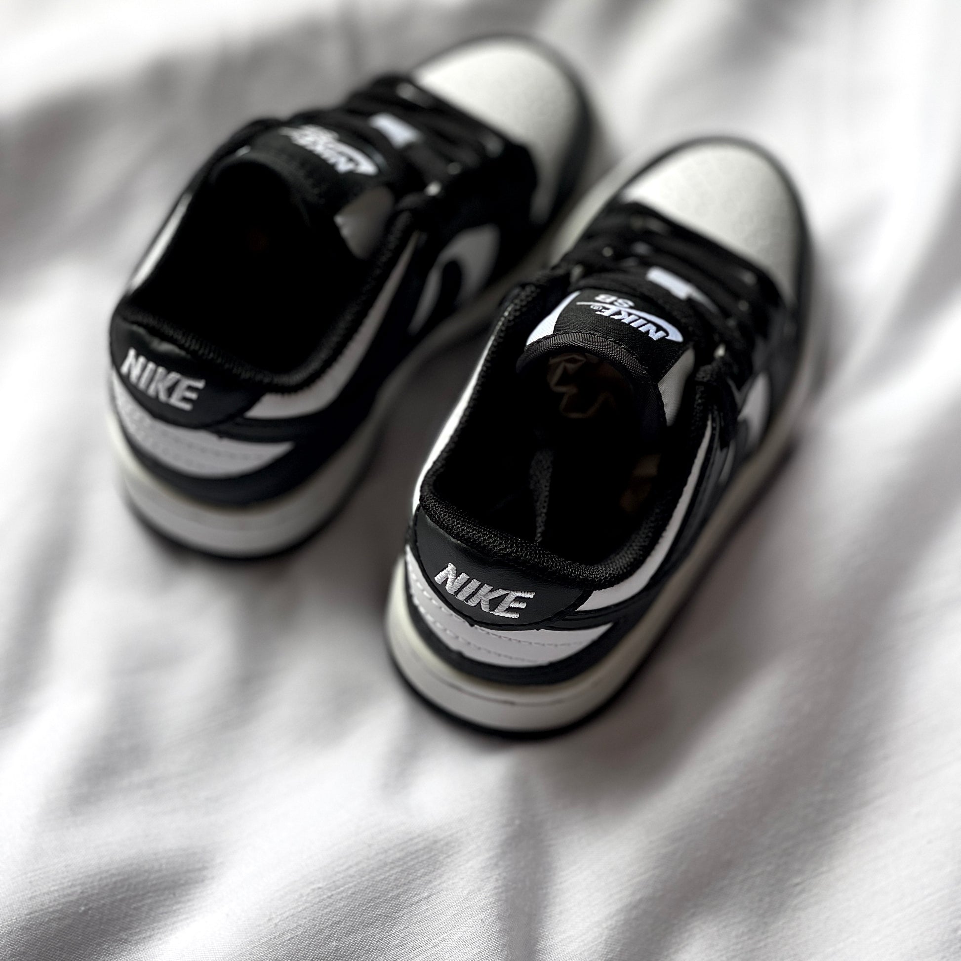 Rear view of Nike Dunk Low Panda kids’ sneaker highlighting heel tab, stitching, and two-tone colorway.
