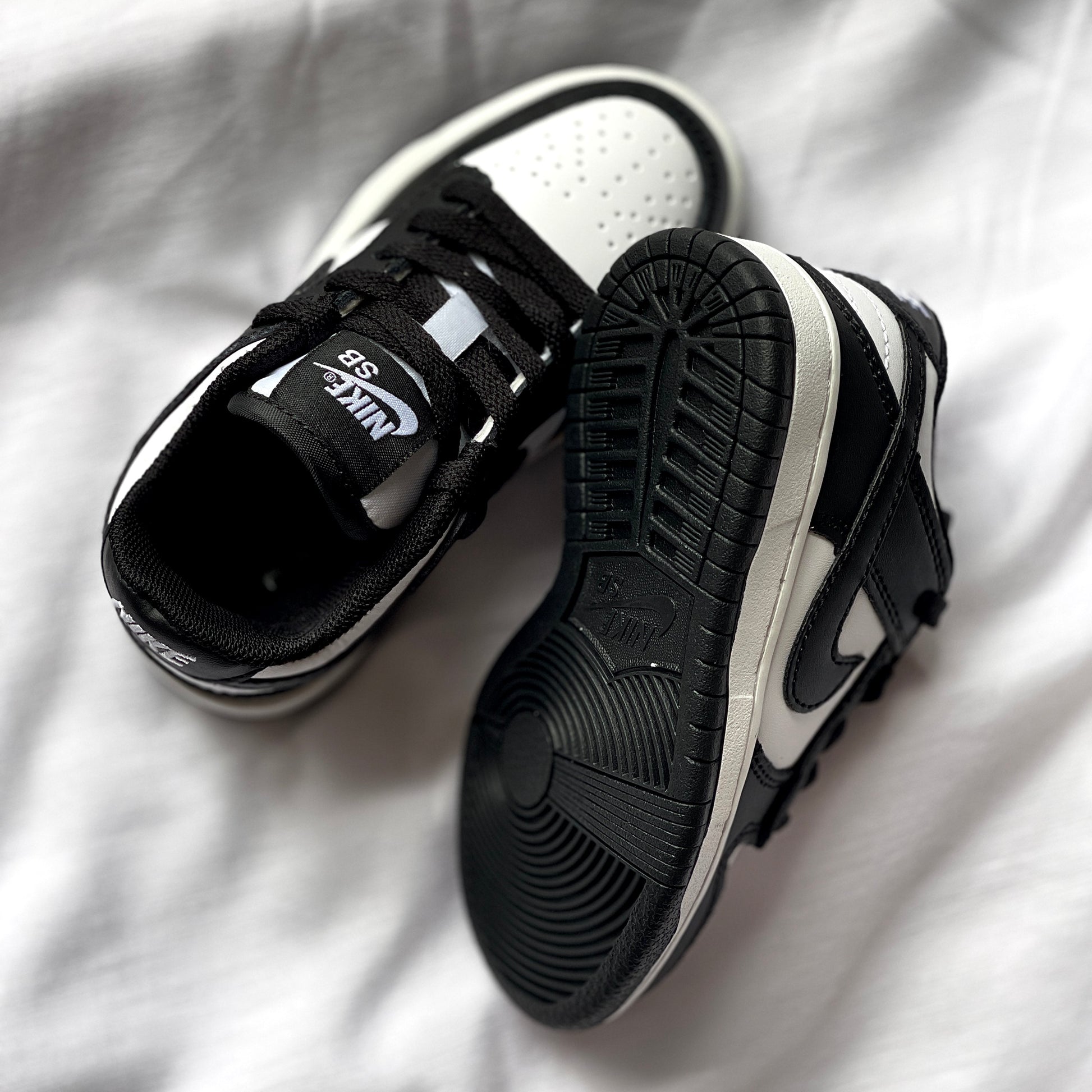 Outsole of Nike Dunk Low Panda kids’ sneaker featuring black rubber traction pattern.