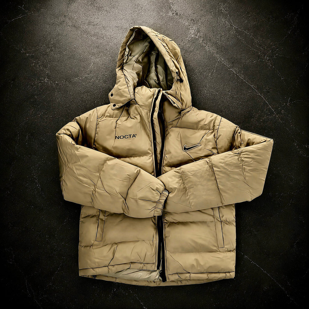 Nike x Drake NOCTA Storm-FIT Skulpeak Puffer Jacket Bone front view featuring insulated quilted construction, full-zip closure, adjustable hood and NOCTA branding.