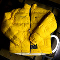 Nike NOCTA Reversible Puffer Jacket University Gold front view on clean background