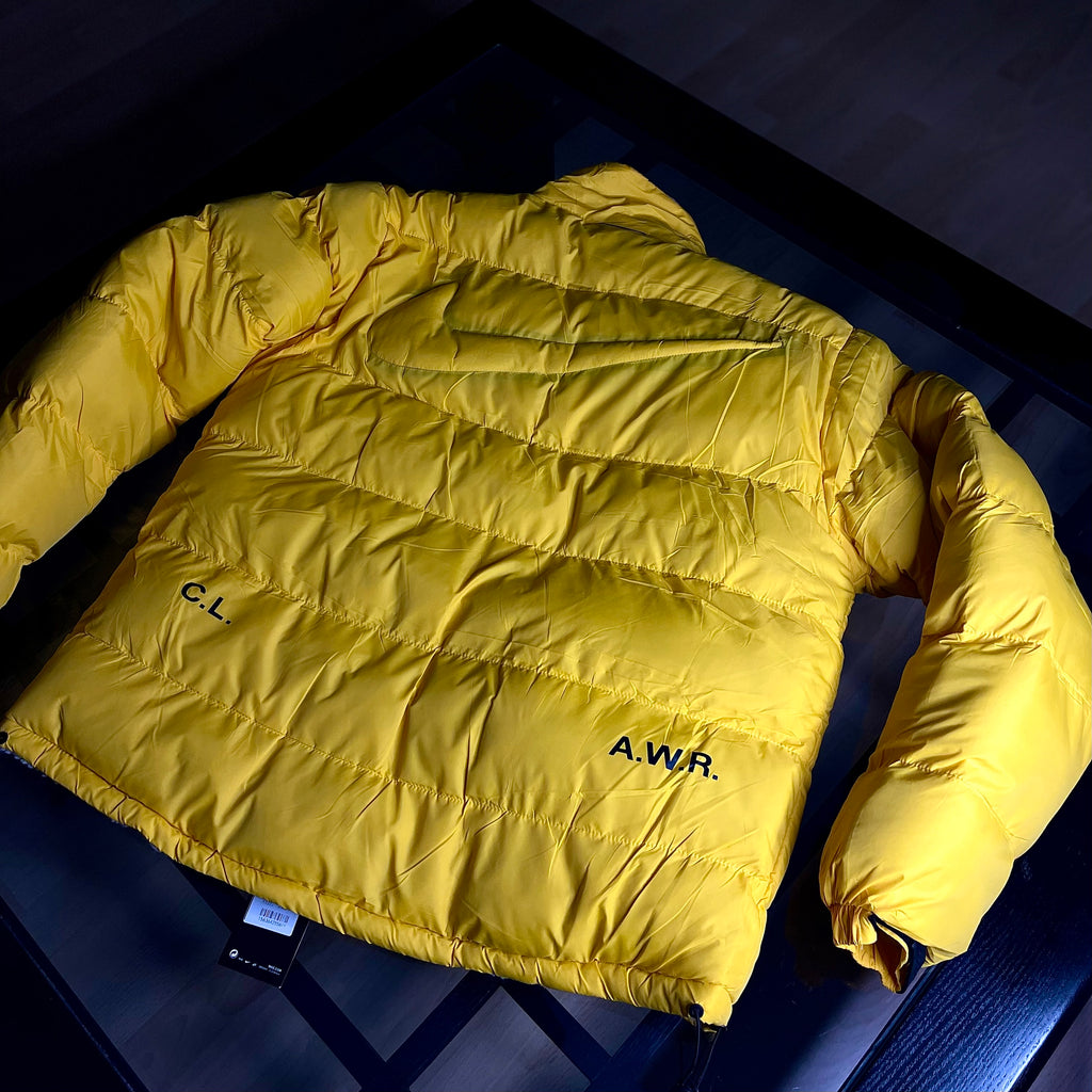 Rear view of Nike NOCTA Reversible Puffer Jacket University Gold highlighting silhouette and panel construction
