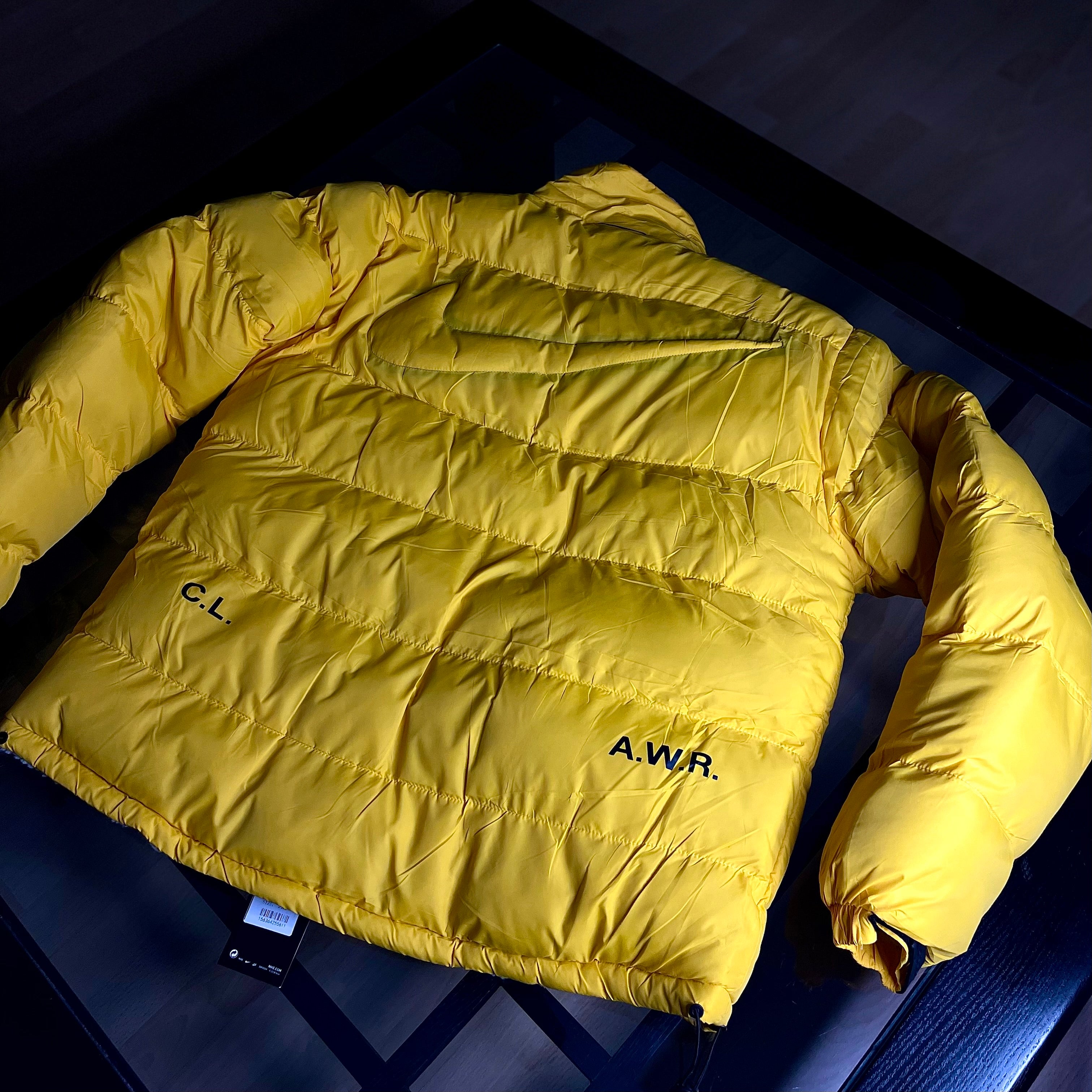 Rear view of Nike NOCTA Reversible Puffer Jacket University Gold highlighting silhouette and panel construction