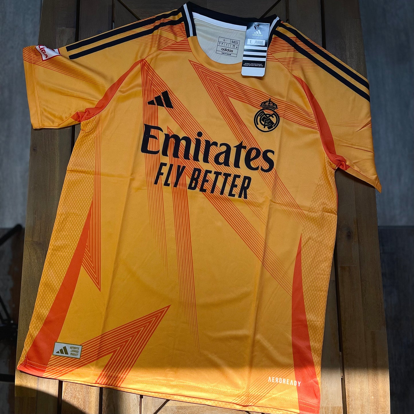 Yellow Real Madrid sports jersey with Emirates and Adidas logos on a wooden surface_1