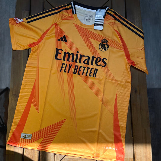 Yellow Real Madrid sports jersey with Emirates and Adidas logos on a wooden surface_1
