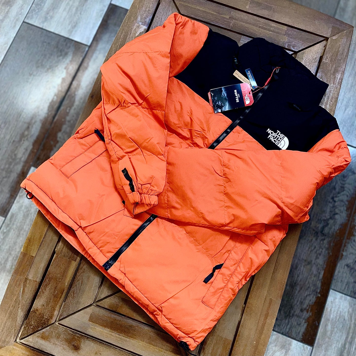 The North Face Puffer Jacket Flare Orange front view — bright orange insulated winter jacket with high collar and logo on chest