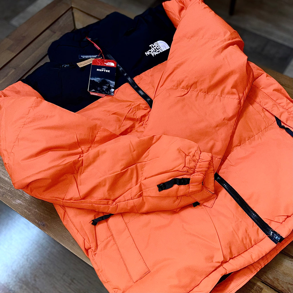 Close-up of The North Face Puffer Jacket Flare Orange fabric and logo — premium nylon shell with detailed stitching and embroidered branding