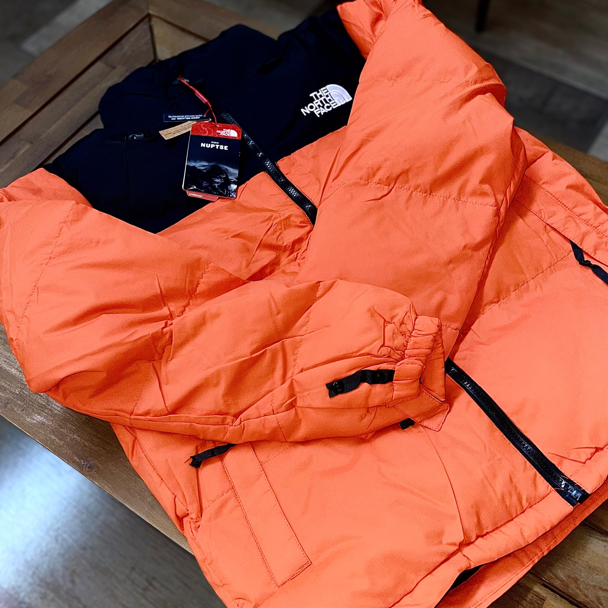 Close-up of The North Face Puffer Jacket Flare Orange fabric and logo — premium nylon shell with detailed stitching and embroidered branding
