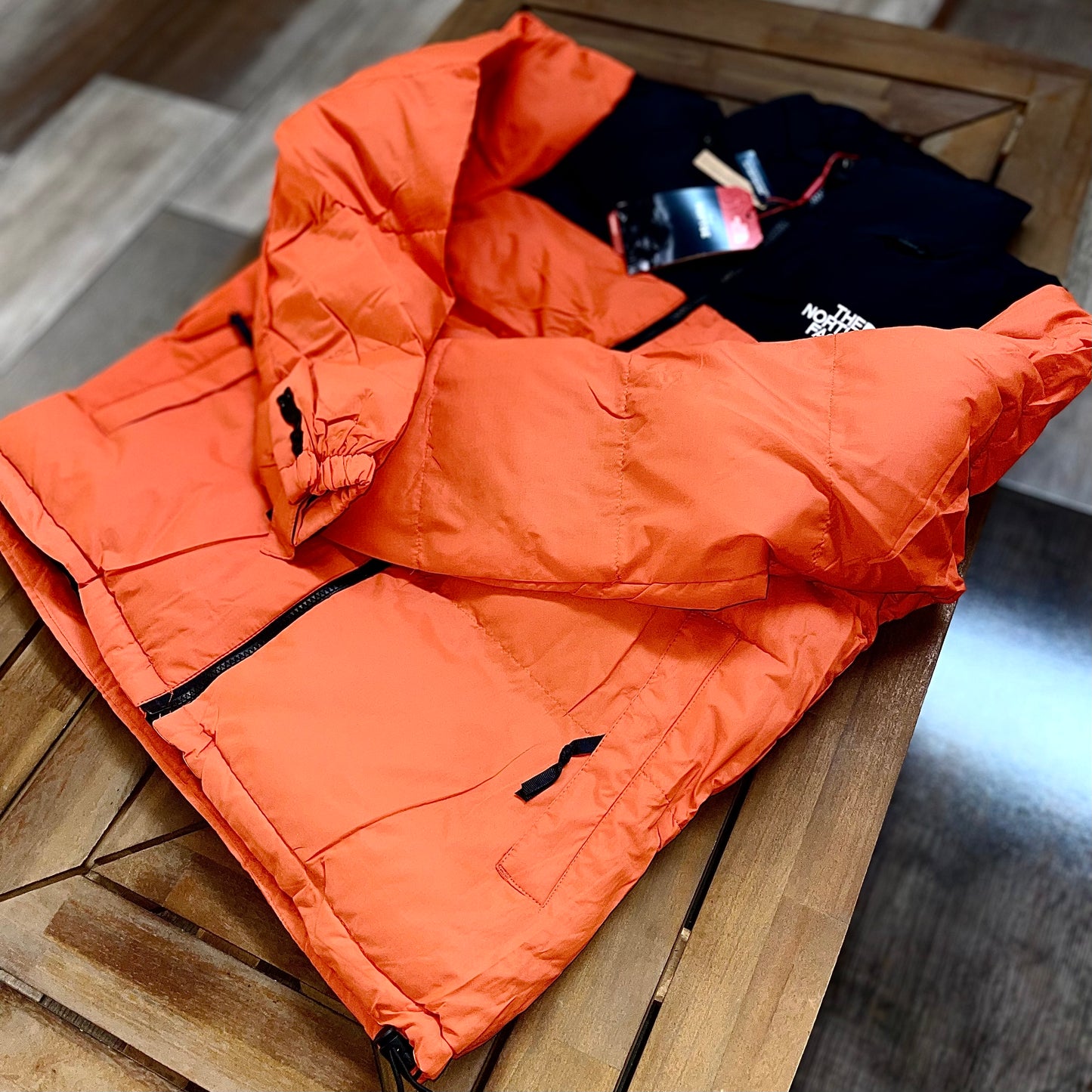 Side view of The North Face Puffer Jacket Flare Orange — puffy insulated silhouette with zip pockets and elastic cuffs